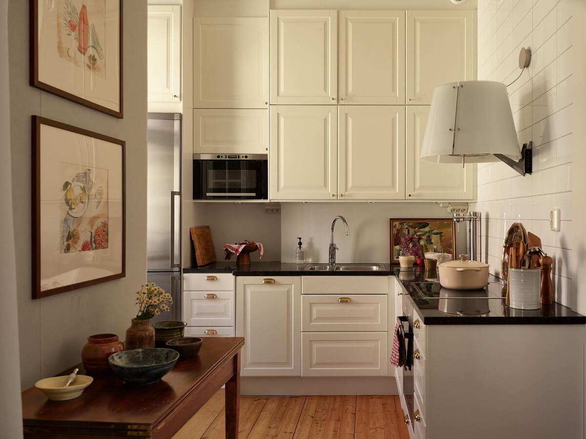 Características de época e cores claras em um apartamento de um quarto 6 cozinha branca com armários superiores duplos